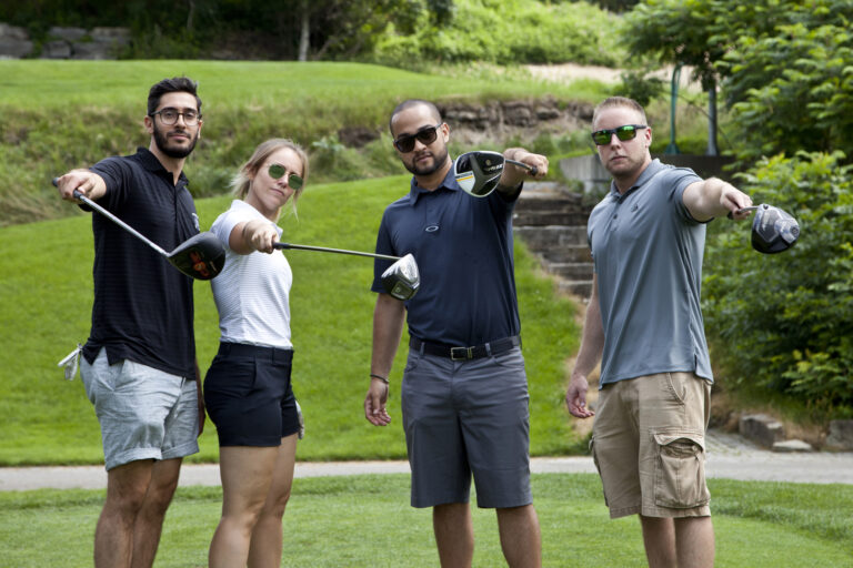 Four golf players pose with their clubs.