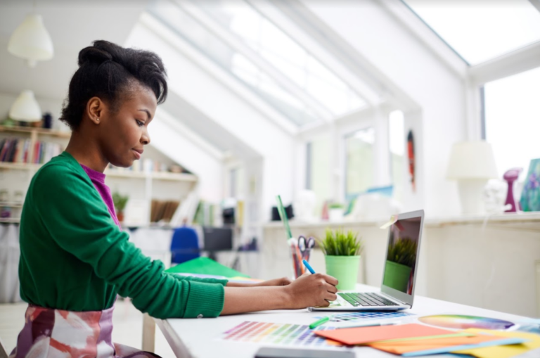 A woman works at a brightly lit table.