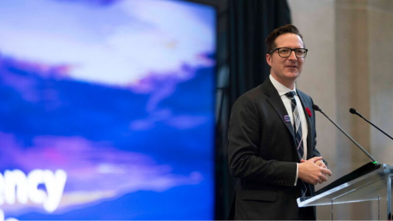 A man at a podium delivers a speech to a professional audience.