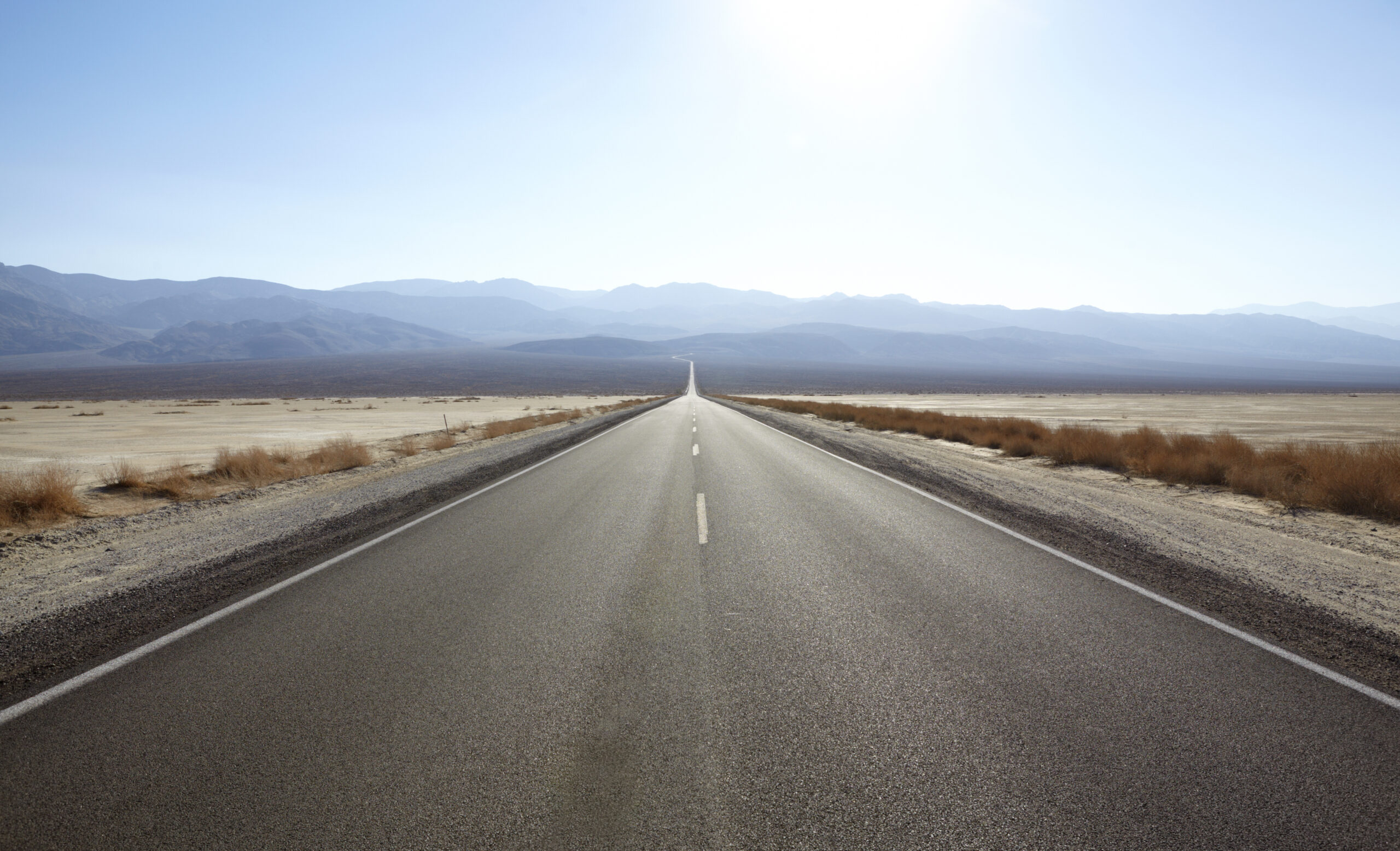 A long barren road into a sunny valley.
