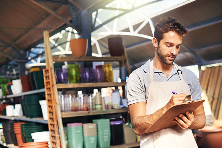 A man looks at a clipboard in a garden centre