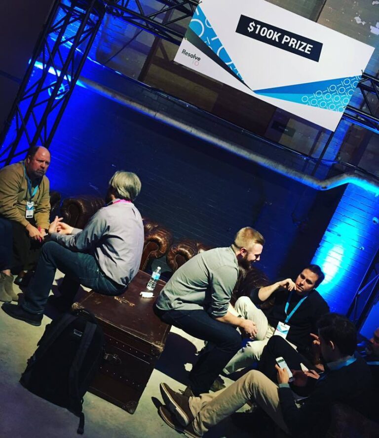 People talk in a backstage seating area.