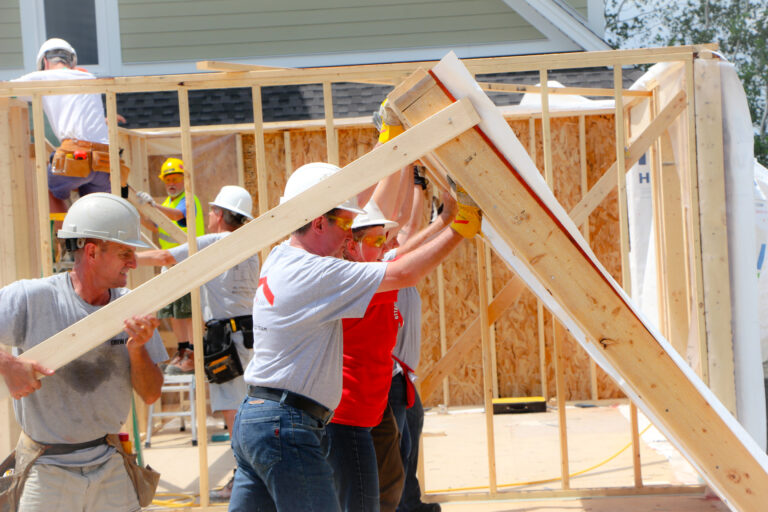 A team of people raise a wall on a build site