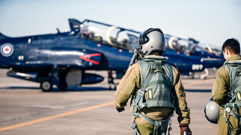 A fighter pilot walks toward his jet on the tarmac.