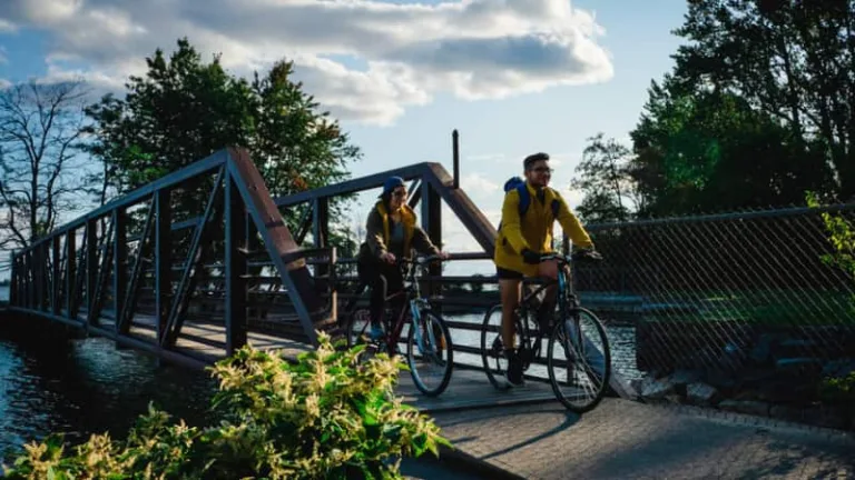 Two people riding bikes are about to finish crossing a bridge.