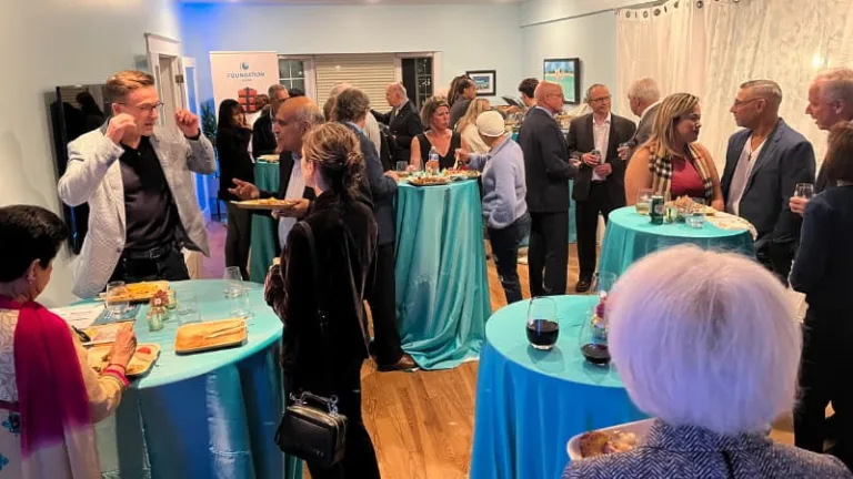 People congregate in a private home around some dinner tables for a fundraiser
