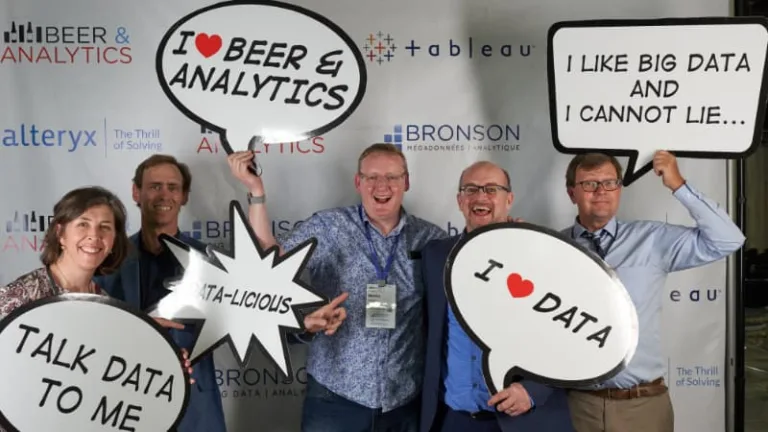 A group of colleague pose excitedly to announce the beer and analytics event