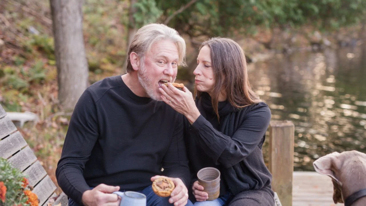 Krista and Todd Gill sit at a waterfront eating cookies.