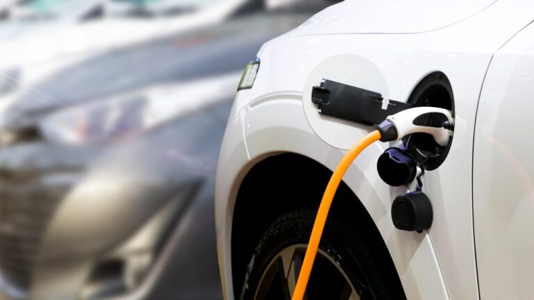 Photo of an electric vehicle charger attached to a white car.