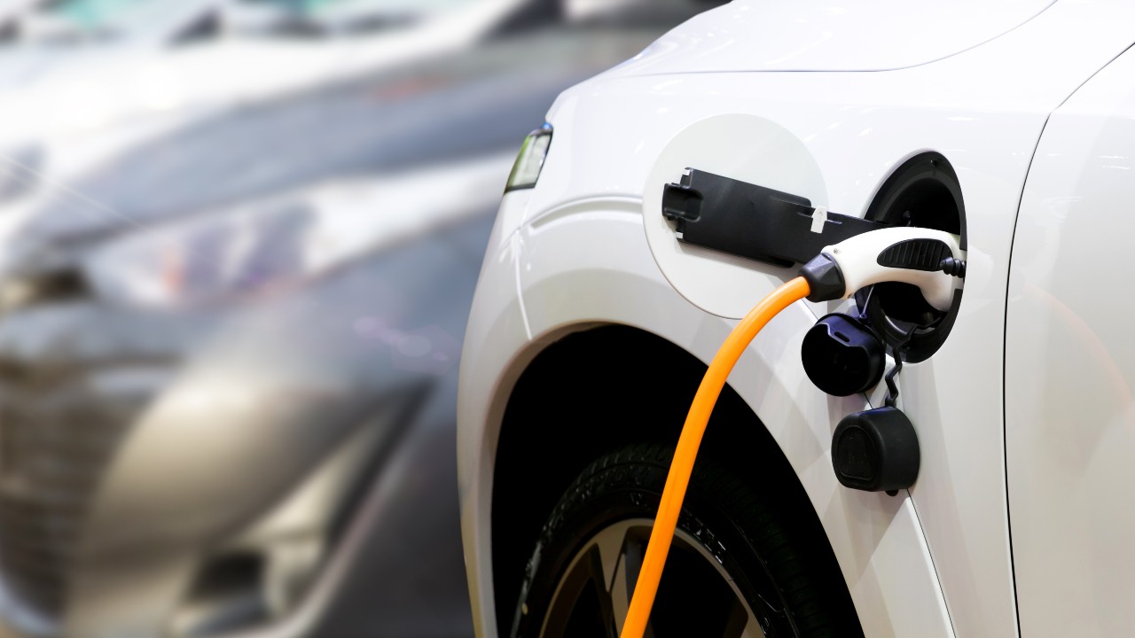 Photo of an electric vehicle charger attached to a white car.