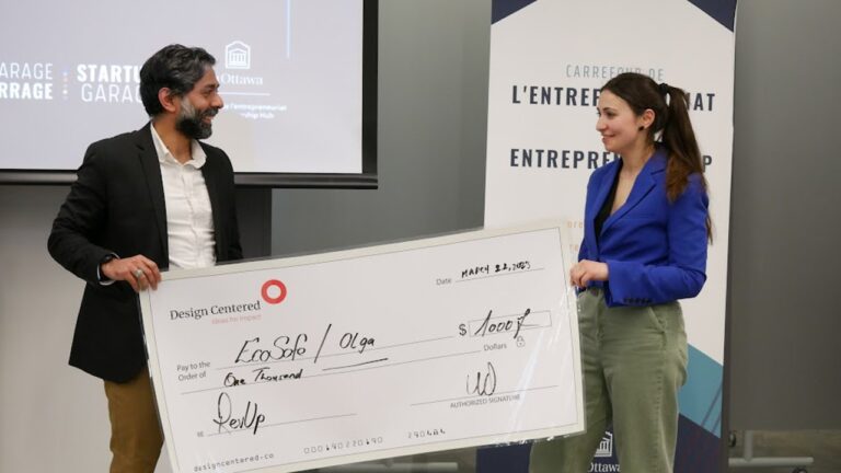 Urooj Qureshi (left) presents an oversized cheque for $1,000 to tech startup EcoSafeSense and CEO Olga Koppel with the first Impact Centered Award.