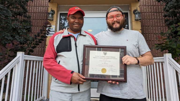 Jon (right) and Salus Community Developer Théoneste (left) holding Jon’s high school diploma