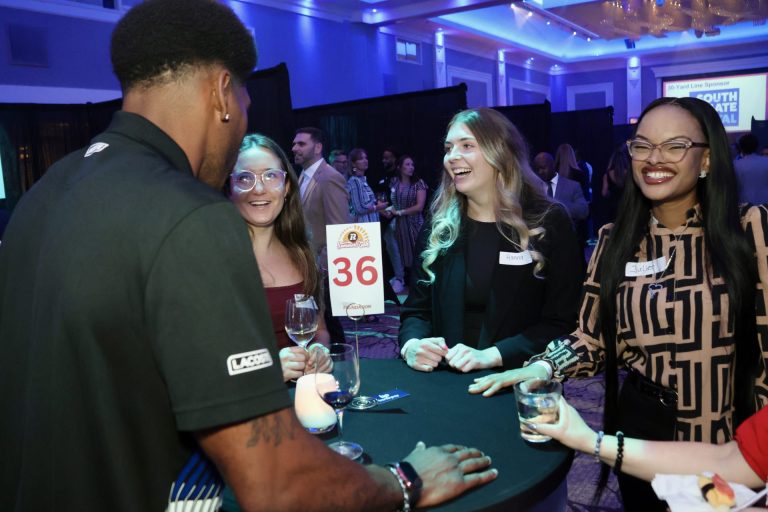 Former Redblacks defensive back Jonathan Rose seen networking at the Infinity Convention Centre with, from left, Paige McKenna (Scrivens Insurance), Hanna Jackson (CAPCORP Financial) and Juliet Chukwuma at the Redblacks Summer Rush networking event and fundraiser for OSEG Foundation's Back to School Initiative. Photo by Caroline Phillips