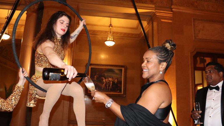 An aerialist pours champagne for a guest. Photo by Mia Jensen