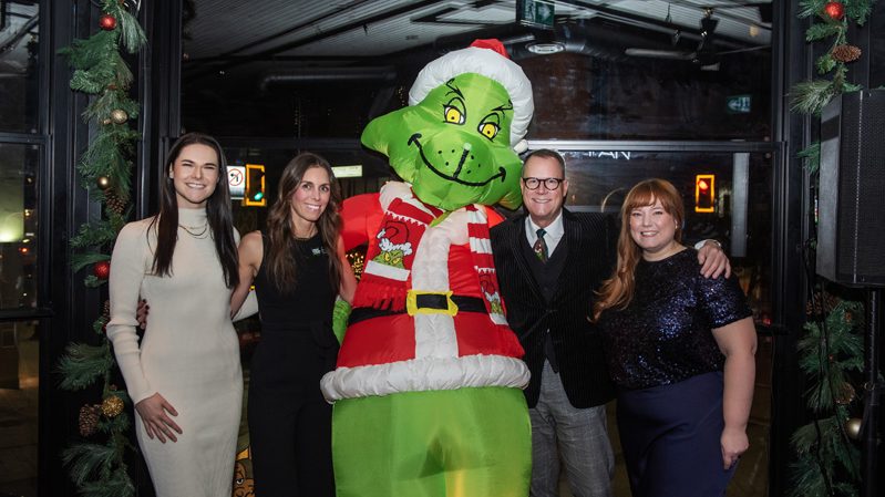 Sarah Langham (SOGH), Emma Bernans (SOGH), John Peters (Gowling WLG and Governance Committee/Honorary Officer Emeritus of Shepherds of Good Hope and Meighan Hartley (SOGH) posing with the Grinch at SOGH Foundation Ginch Dinner, Harmon’s Steak House, Nov 27, 2025. Photo by Tia MacPherson for OBJ.