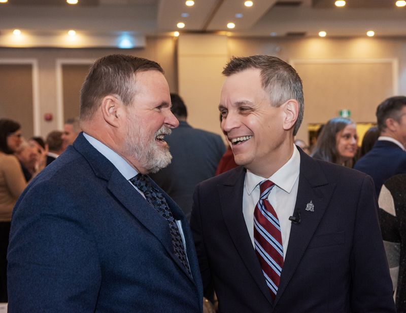Robert Merkley sharing a laugh with Mayor Mark Sutcliffe, at GOHBA Breakfast with the Mayor, Saint Elias Banquet Centre, Jan 8, 2026.