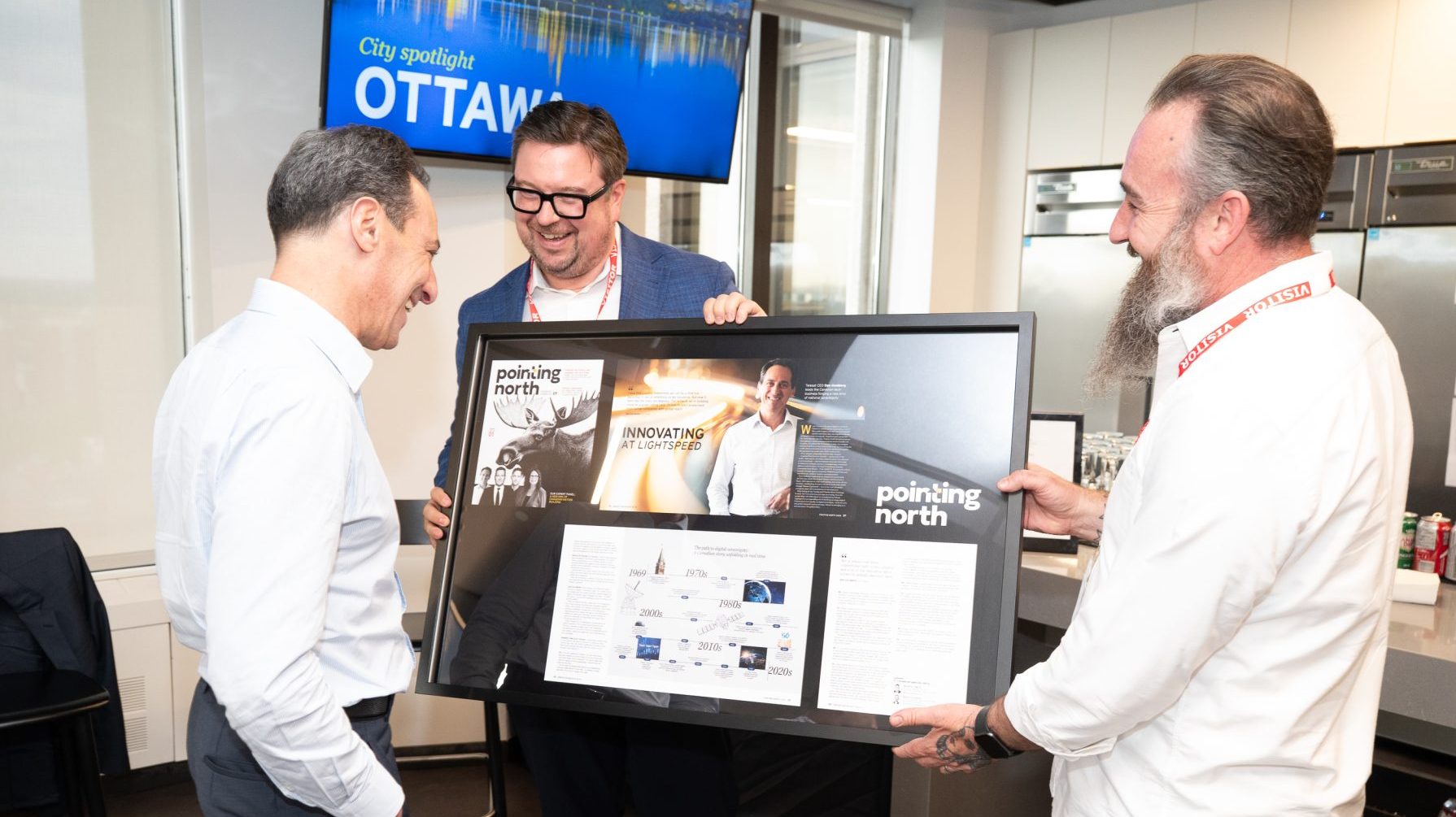 Dan Goldberg (Telesat), Aaron Smith (EY Canada) and Arryn Blumberg (EY Canada) present a gift to Dan Goldberg at the executive dialogue on Ottawa’s economic future and innovation agenda at Telesat headquarters, May 26, 2026. Photo by Mark Holleron for OBJ.