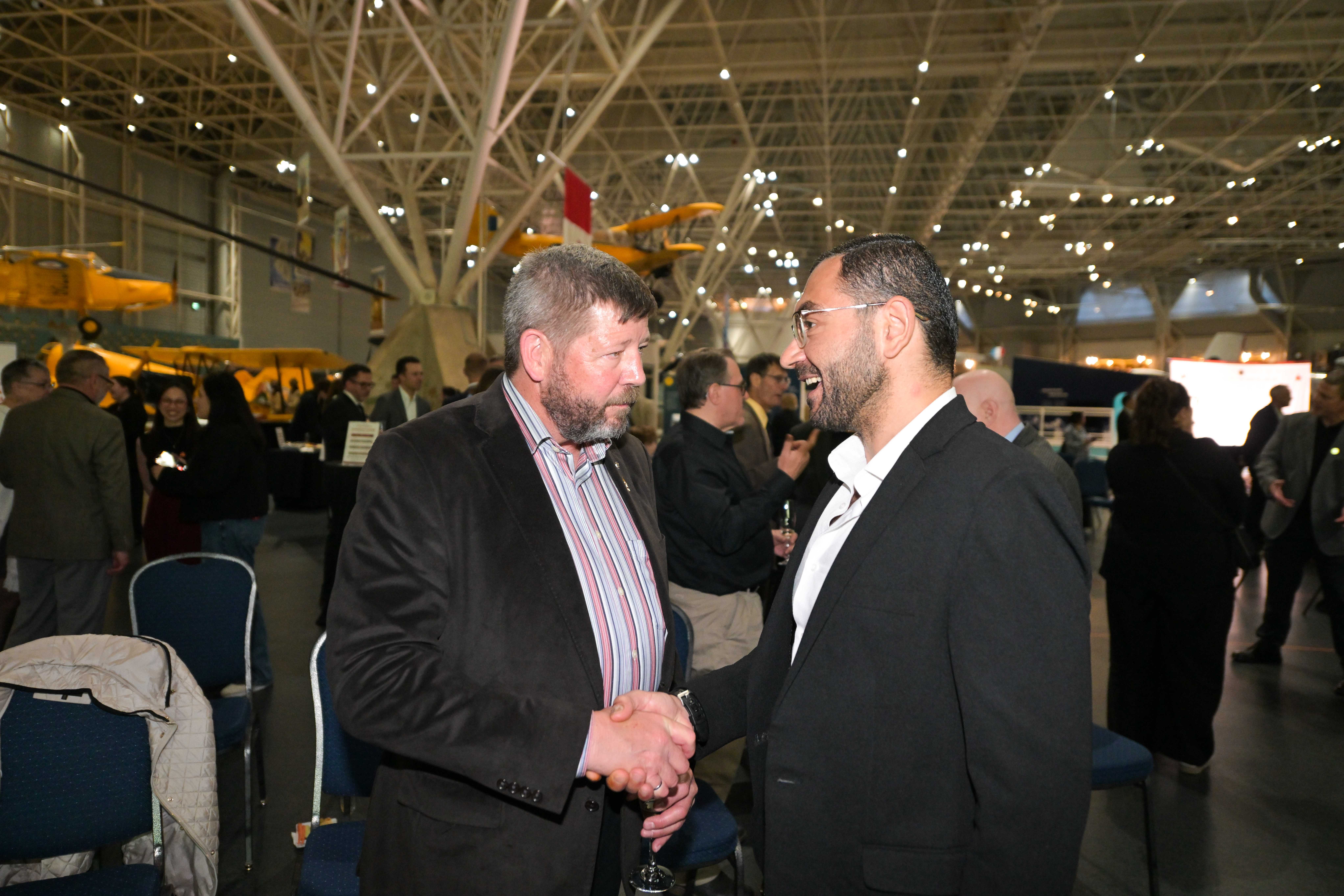 Alan Mulawyshyn (Executive Director, VHC) and Ala&rsquo;a Shadid (Executive Director, Multifaith Housing Initiative) greet one another during Veterans&rsquo; House Canada&rsquo;s Andy Carswell Building 5th Anniversary celebration at the Canadian Aviation and Space Museum. Photo by James Park.